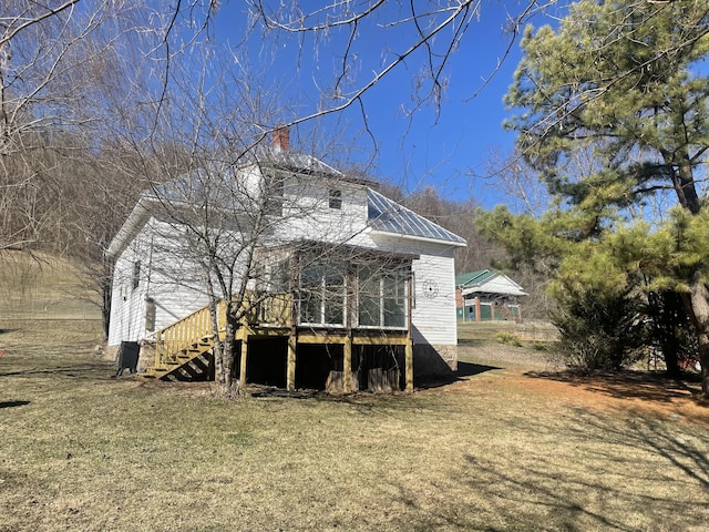 back of house with metal roof, a lawn, and stairway