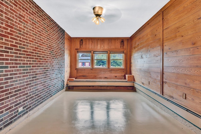 empty room with wood walls, a baseboard radiator, brick wall, and concrete floors