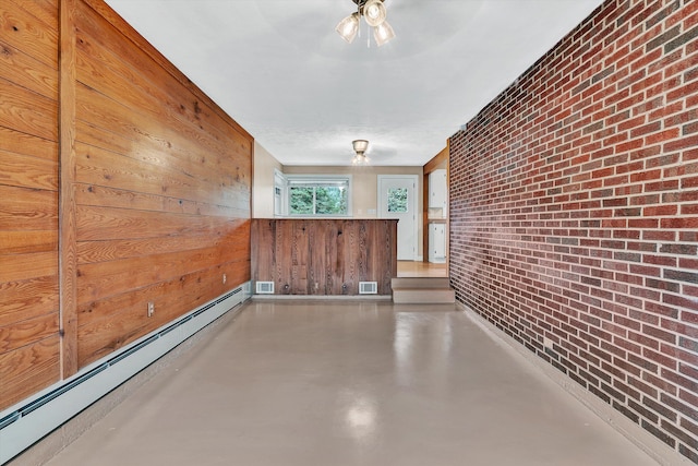 hall with baseboard heating, wooden walls, concrete flooring, and brick wall