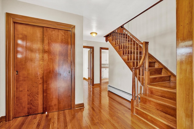 staircase with hardwood / wood-style floors and a baseboard radiator