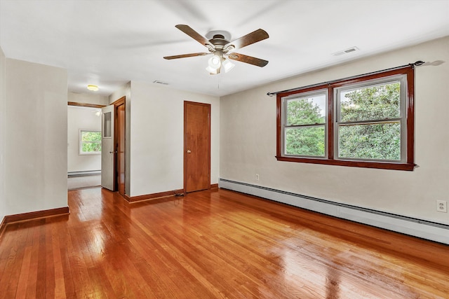 empty room with ceiling fan, a healthy amount of sunlight, a baseboard radiator, and light hardwood / wood-style flooring