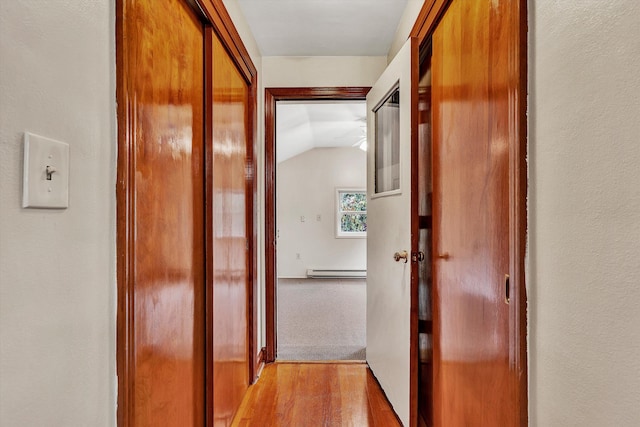 corridor featuring light hardwood / wood-style floors, lofted ceiling, and a baseboard heating unit