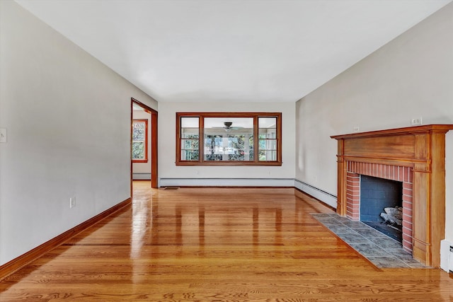 unfurnished living room with a brick fireplace, a baseboard heating unit, and light wood-type flooring