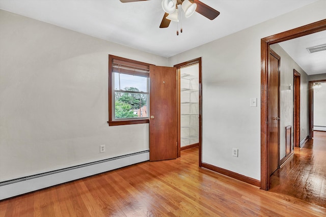 spare room featuring ceiling fan, light hardwood / wood-style floors, and a baseboard heating unit