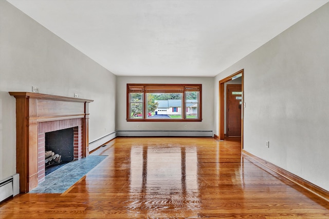 unfurnished living room featuring light hardwood / wood-style floors, baseboard heating, and a brick fireplace