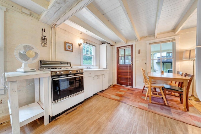 kitchen featuring beamed ceiling, white cabinets, light hardwood / wood-style floors, and white stove