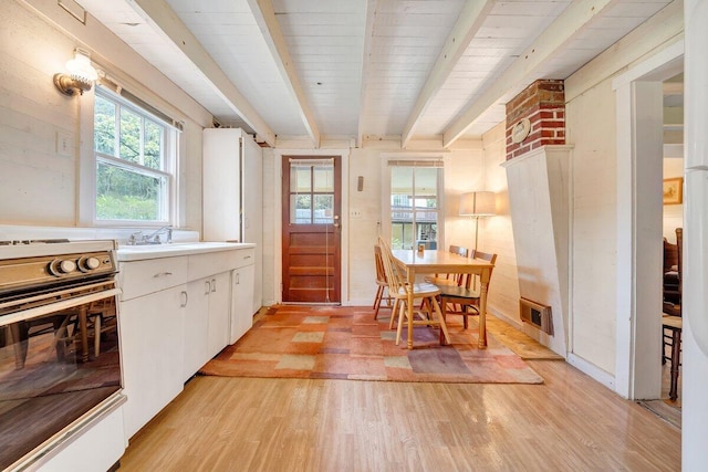 kitchen featuring white cabinets, sink, light hardwood / wood-style flooring, beam ceiling, and range