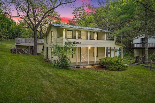 back house at dusk featuring a yard and a balcony