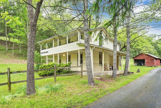 view of front facade with a porch, a balcony, and a front yard