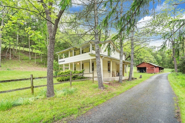 view of side of home featuring an outdoor structure, a porch, and a yard