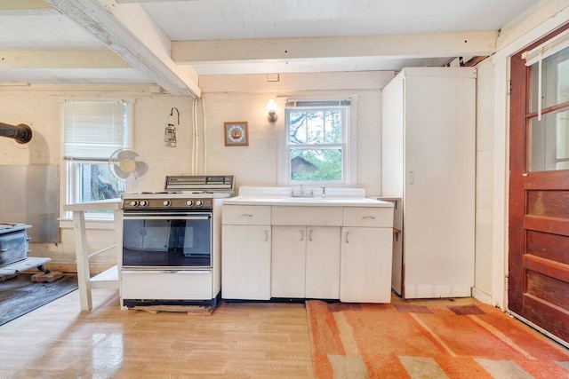 kitchen with white range oven, sink, beam ceiling, white cabinets, and light hardwood / wood-style floors