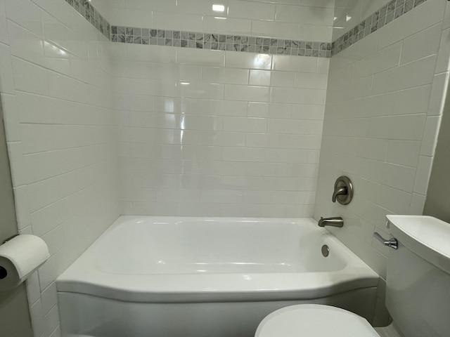 bathroom featuring tiled shower / bath combo and toilet