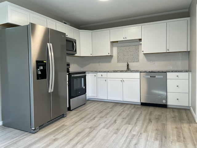 kitchen featuring dark stone counters, sink, ornamental molding, appliances with stainless steel finishes, and white cabinetry