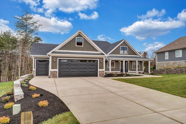 craftsman-style home with a garage, covered porch, and a front lawn