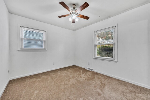 empty room featuring plenty of natural light, ceiling fan, and light carpet