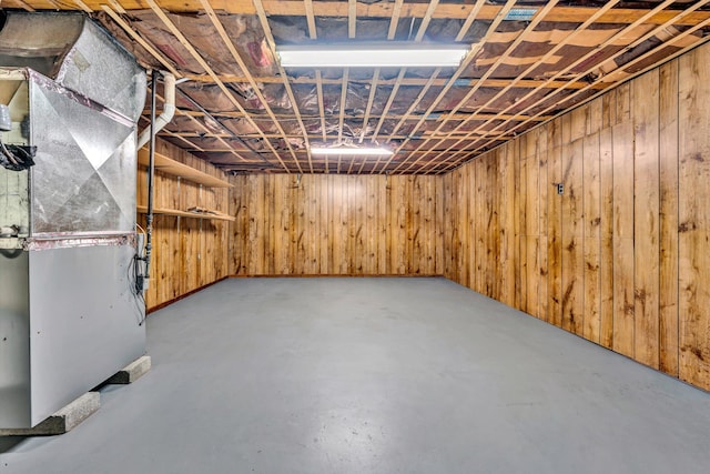 basement featuring heating unit and wood walls