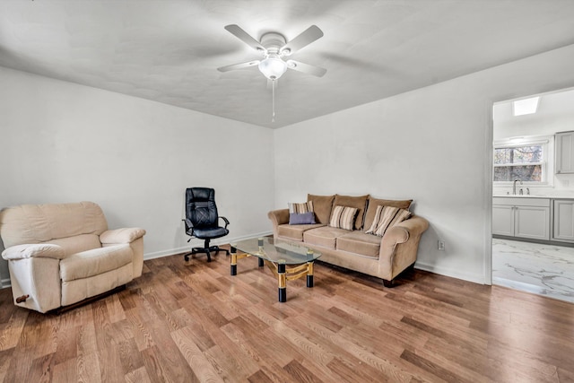 living room featuring light wood-type flooring, ceiling fan, and sink