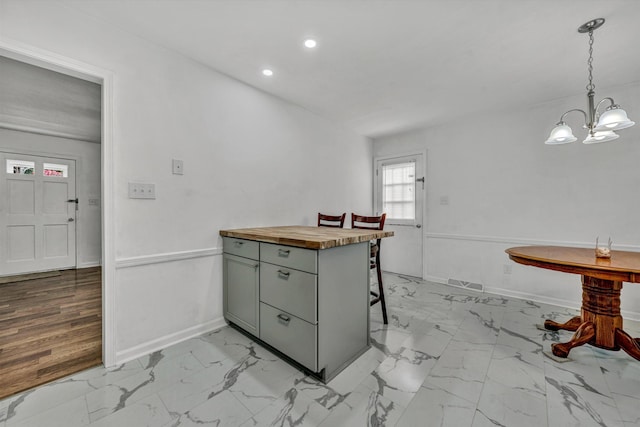 kitchen with wood counters, a kitchen breakfast bar, hanging light fixtures, light wood-type flooring, and a notable chandelier