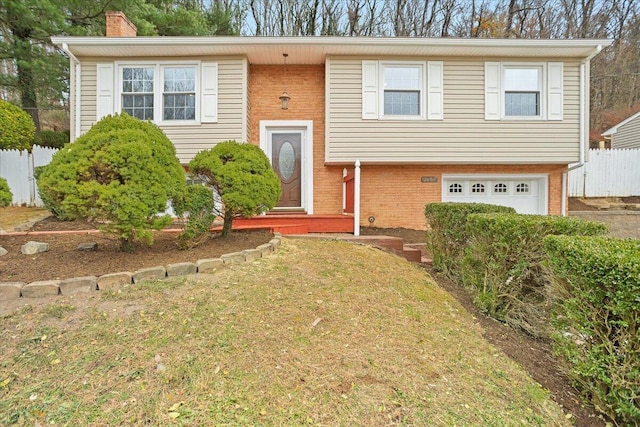 bi-level home with a garage and a front lawn