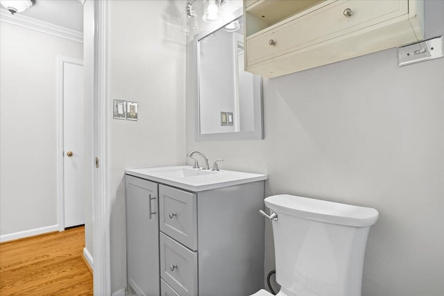 bathroom featuring crown molding, toilet, vanity, and hardwood / wood-style flooring