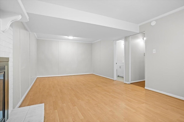 basement with a fireplace, ornamental molding, and light wood-type flooring