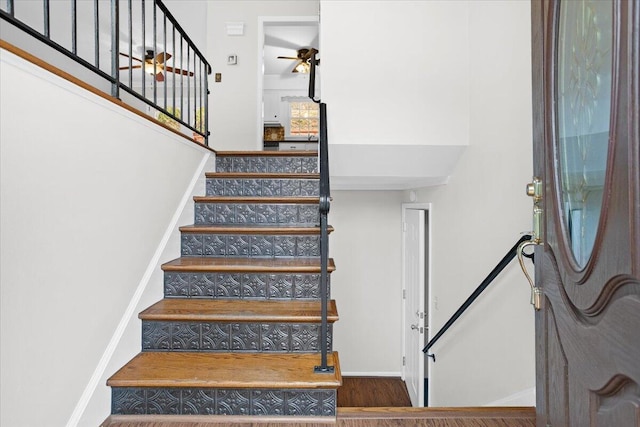 stairs featuring ceiling fan and hardwood / wood-style flooring