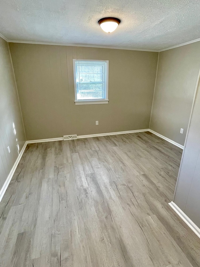 spare room featuring crown molding, light hardwood / wood-style flooring, and a textured ceiling