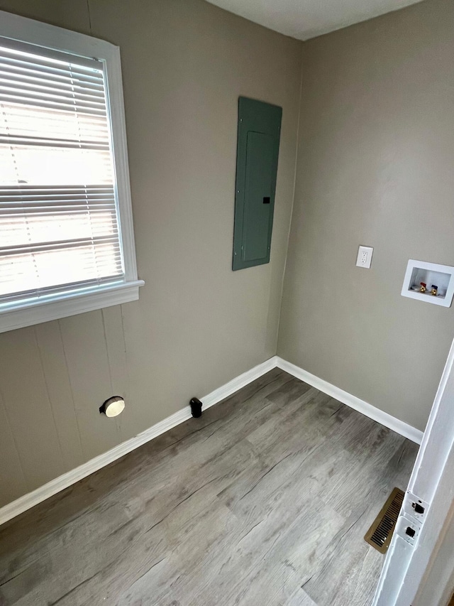 clothes washing area featuring electric panel, light hardwood / wood-style flooring, and hookup for a washing machine