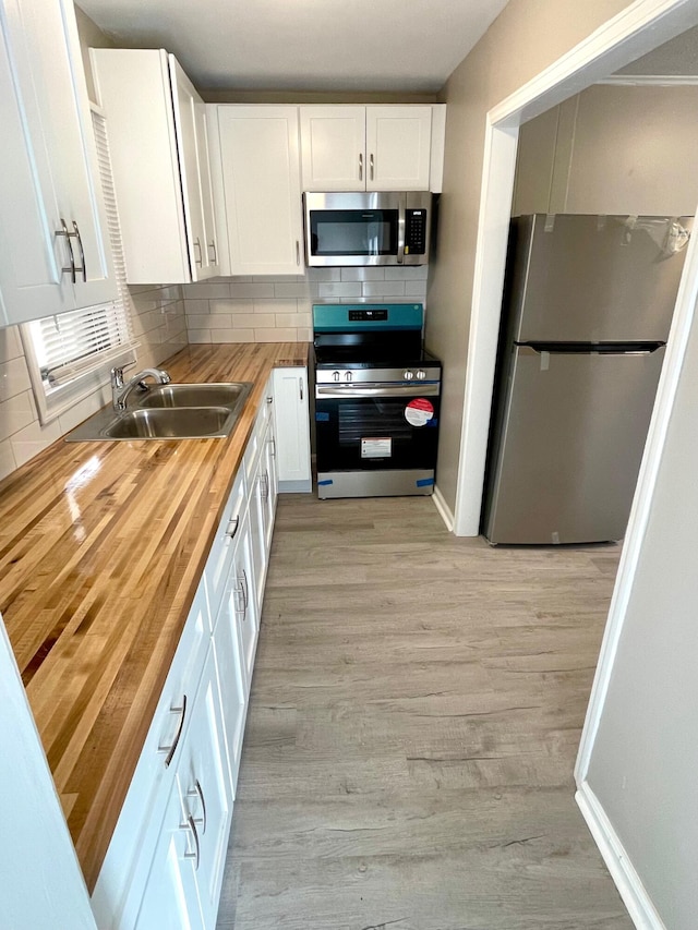 kitchen featuring wood counters, white cabinets, sink, decorative backsplash, and appliances with stainless steel finishes