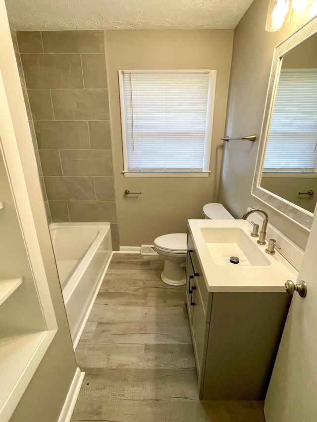 full bathroom with hardwood / wood-style floors, vanity, toilet, a textured ceiling, and shower / bathtub combination