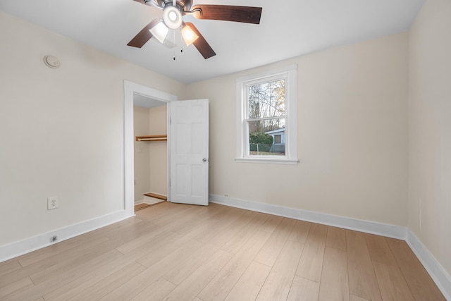 unfurnished bedroom with ceiling fan, a closet, a spacious closet, and light wood-type flooring