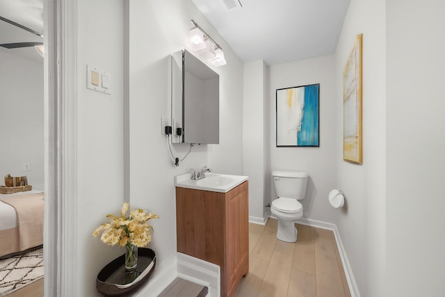 bathroom with vanity, hardwood / wood-style flooring, toilet, and ceiling fan