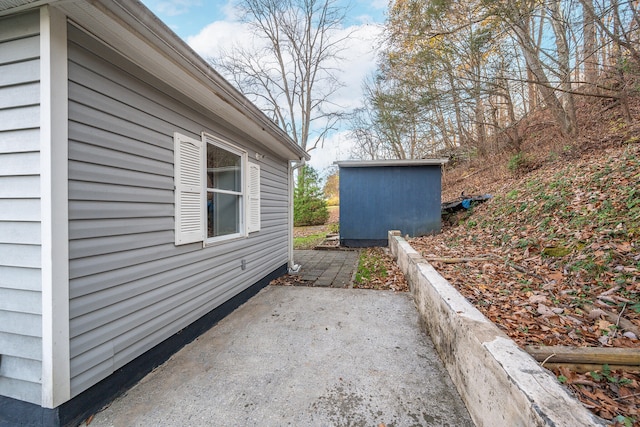 view of home's exterior with a storage unit and a patio area