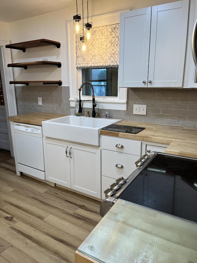 kitchen featuring white cabinets, decorative light fixtures, and butcher block counters