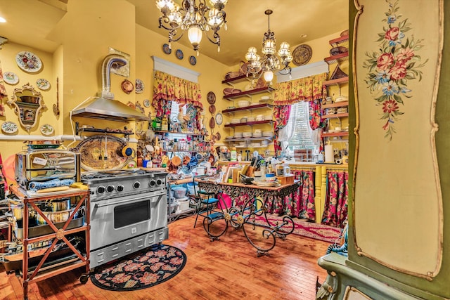 kitchen with high end range, hardwood / wood-style flooring, an inviting chandelier, and island exhaust hood