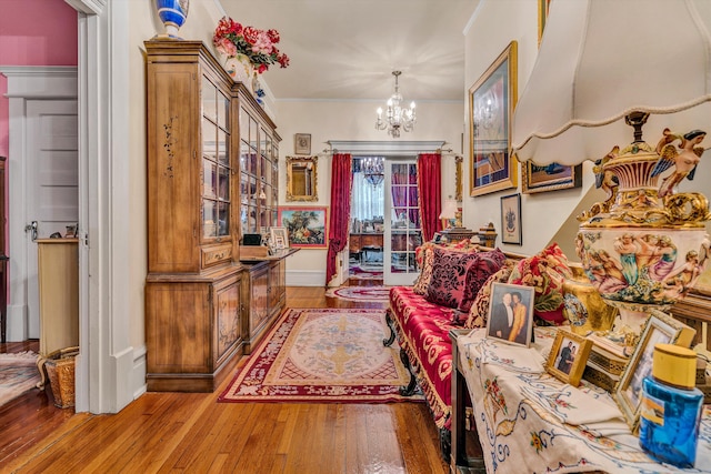 living area featuring wood-type flooring, crown molding, and a notable chandelier