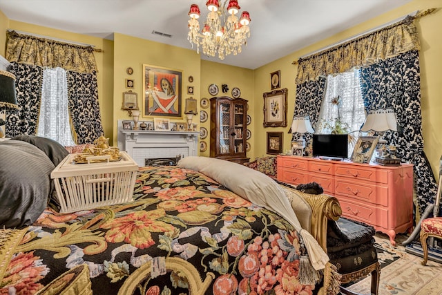 bedroom featuring a fireplace and an inviting chandelier