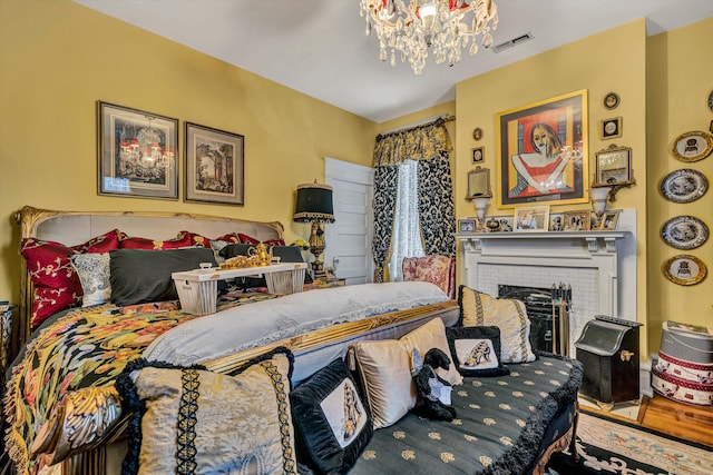 bedroom with hardwood / wood-style flooring, a fireplace, and an inviting chandelier