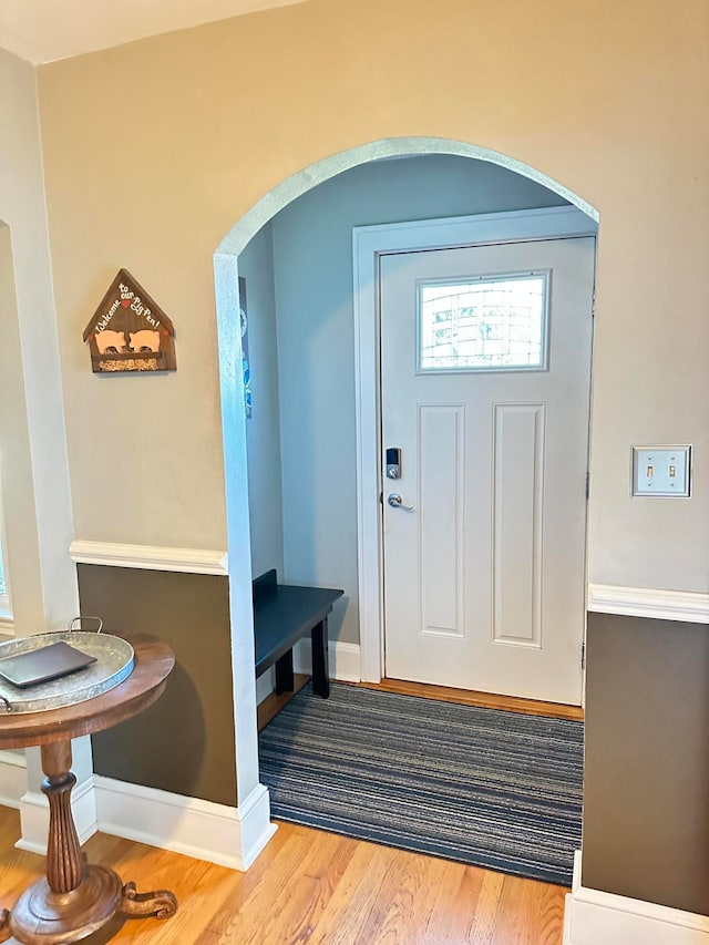 entryway with baseboards, arched walkways, and wood finished floors