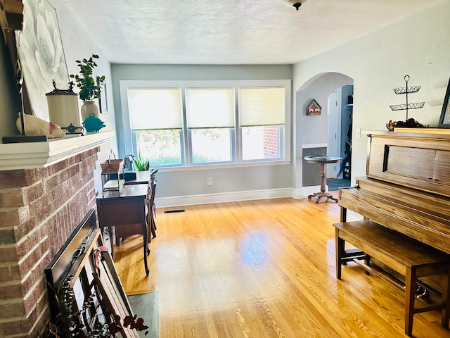 home office with visible vents, baseboards, arched walkways, and light wood finished floors