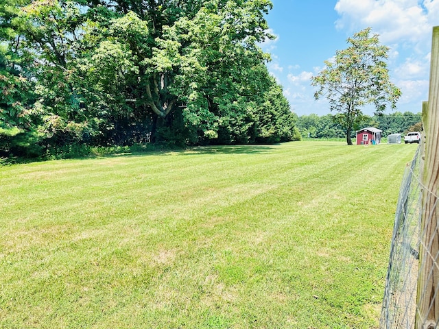 view of yard with an outbuilding, a storage unit, and fence