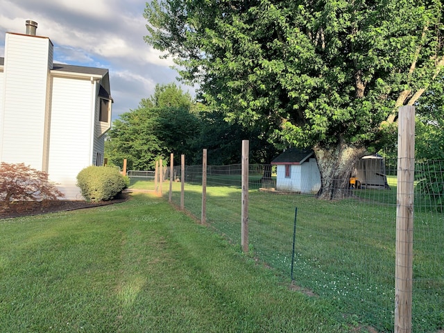 view of yard featuring an outbuilding, fence, and a shed