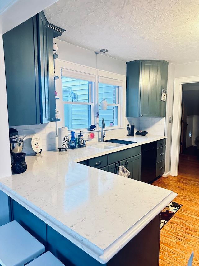 kitchen featuring backsplash, sink, decorative light fixtures, and light hardwood / wood-style flooring