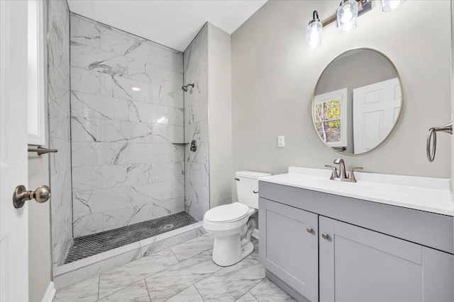 bathroom with a tile shower, vanity, and toilet