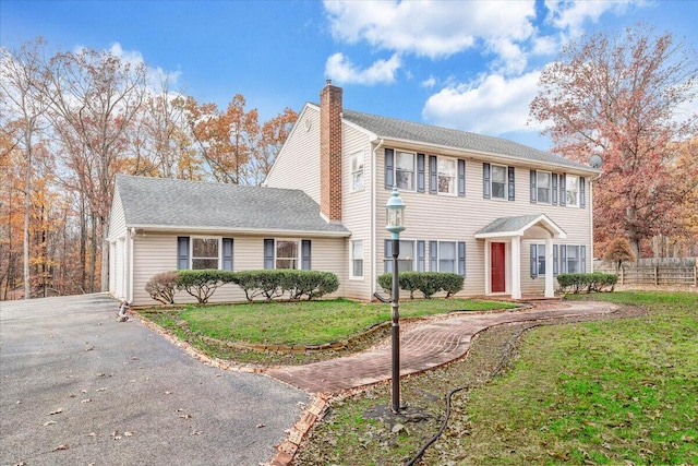 colonial house featuring a front lawn and a garage