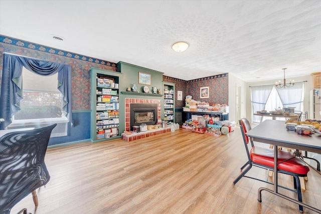 dining room featuring hardwood / wood-style flooring, a brick fireplace, a chandelier, and a textured ceiling