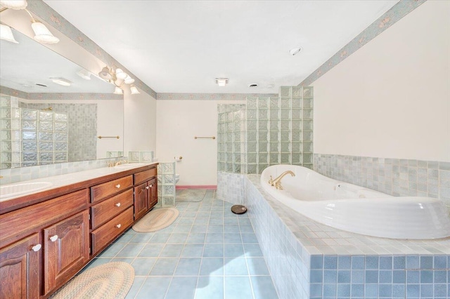 bathroom with tile patterned flooring, vanity, and tiled tub