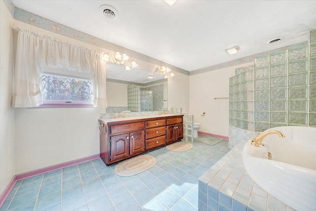 bathroom with a relaxing tiled tub, tile patterned floors, vanity, and toilet