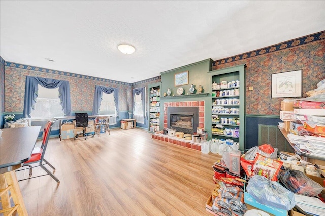 living room featuring hardwood / wood-style flooring, a brick fireplace, and a textured ceiling