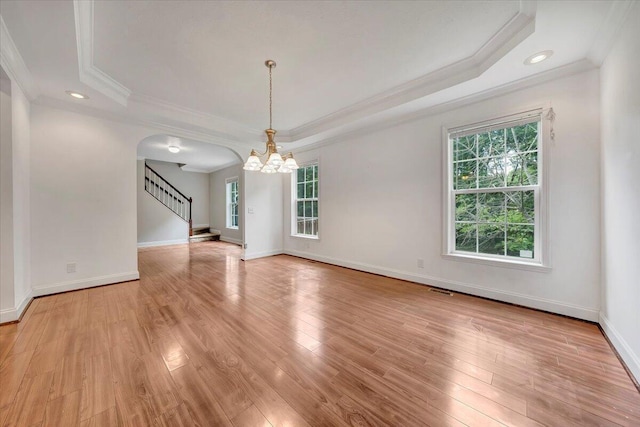 unfurnished room with a healthy amount of sunlight, crown molding, light hardwood / wood-style flooring, and a tray ceiling